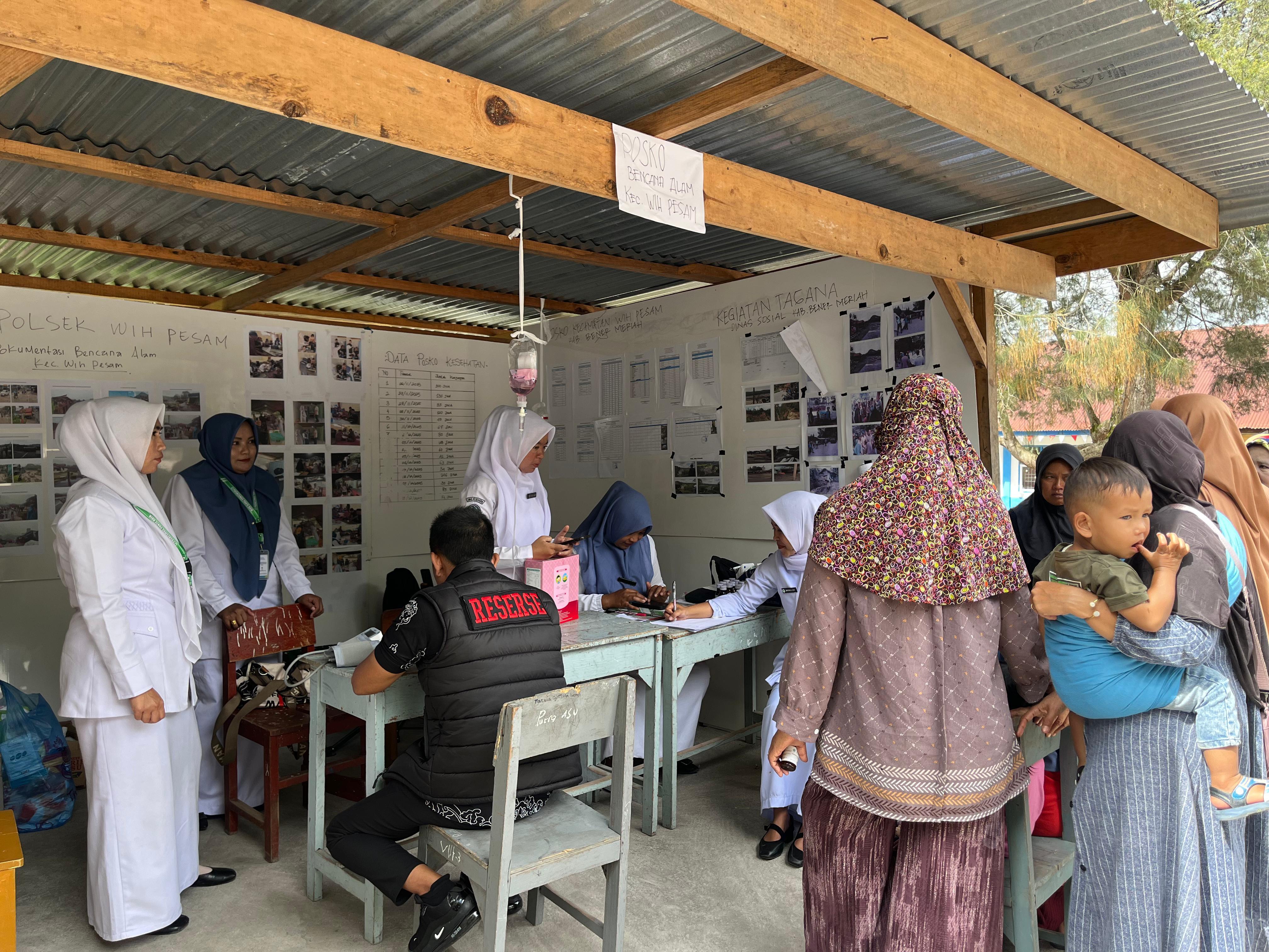 Tenaga Kesehatan dari Puskesmas sedang memberikan pelayanan kesehatan kepada warga di desa terisolir akibat bencana.