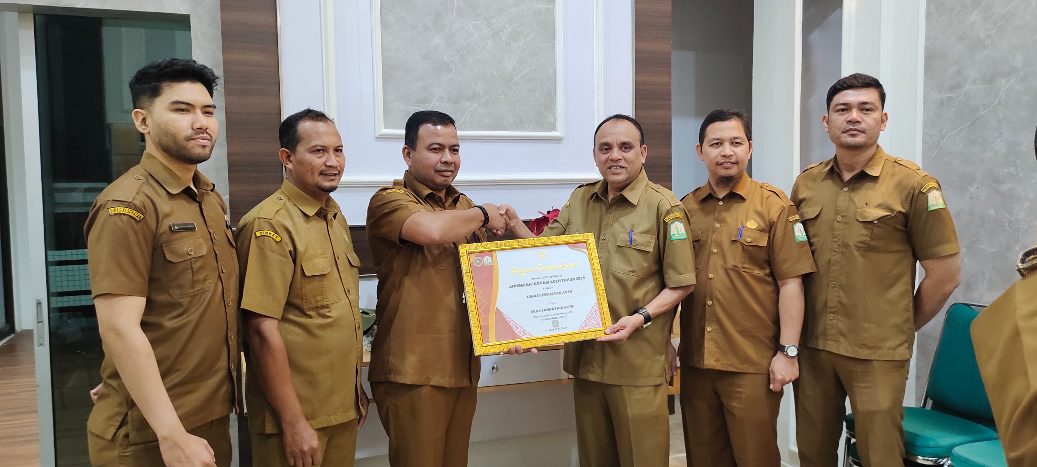 Kepala Bidang Riset dan Inovasi Daerah Bappeda Aceh, Muhajir, ST, MT, saat menyerahkan penghargaan Anugerah Inovasi Aceh kepada Dinas Kesehatan Aceh sebagai SKPA Sangat Inovatif tahun 2025, dan diterima langsung oleh Plt. Kepala Dinas Kesehatan Aceh, Ferdiyus, SKM, M.Kes, di ruang kerja Kadinkes Aceh, Senin (2/2/2026).